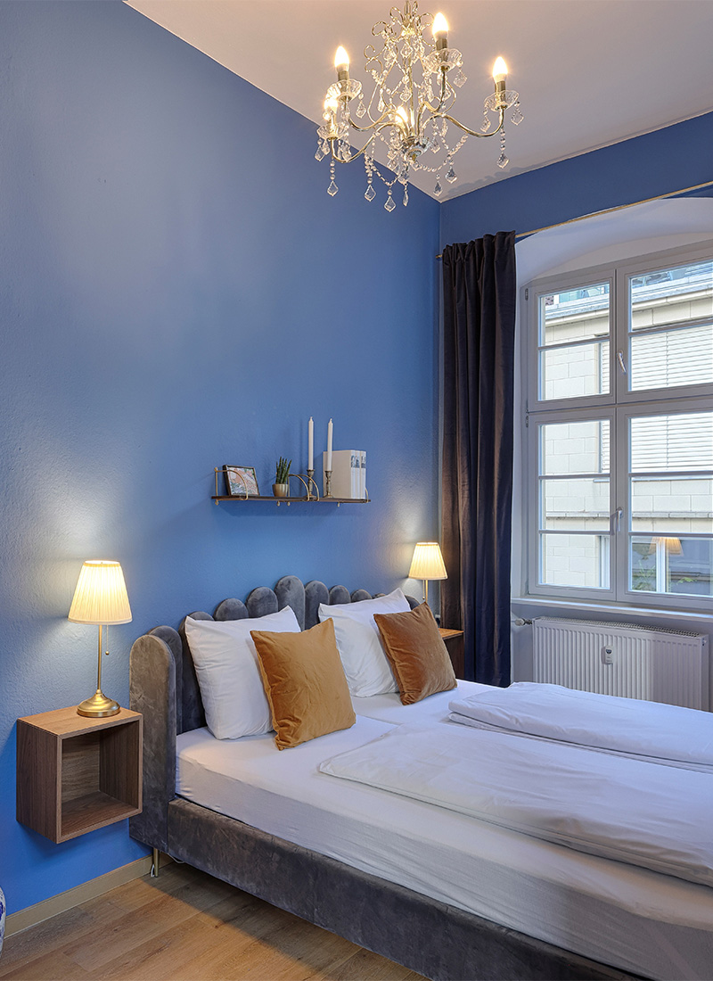 Elegantes Schlafzimmer einer Ferienwohnung in Würzburg mit blauer Wand und Doppelbett