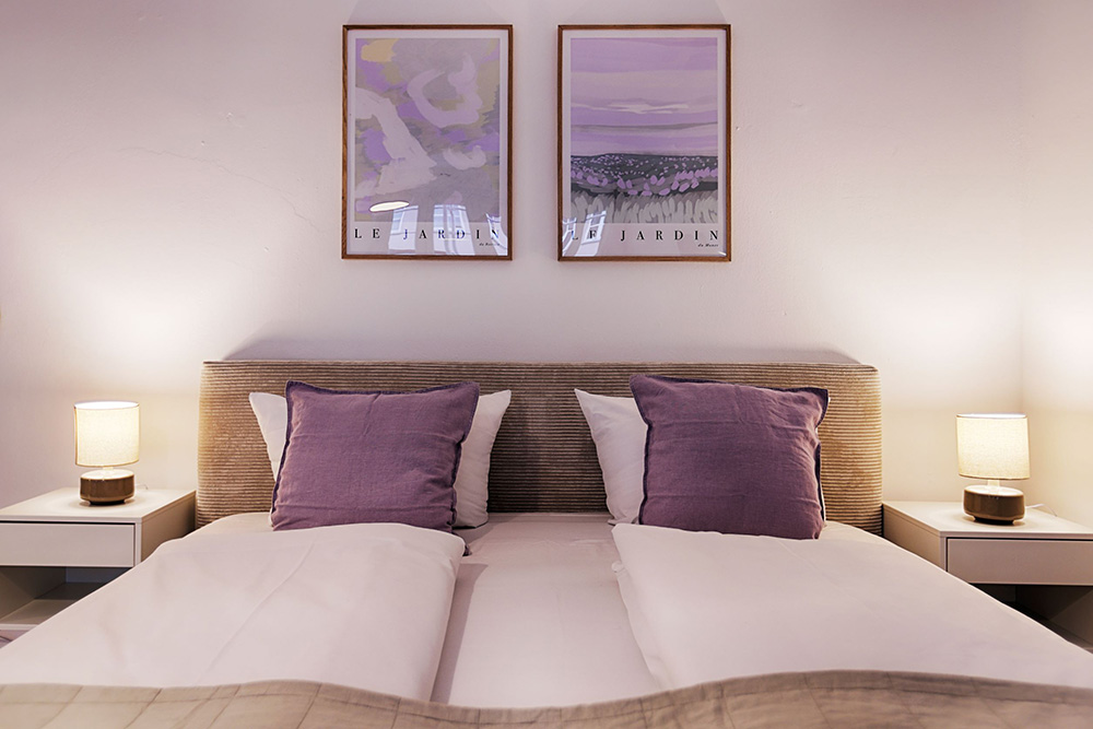 Schlafzimmer einer Ferienwohnung in Würzburg mit Doppelbett und lila Kissen