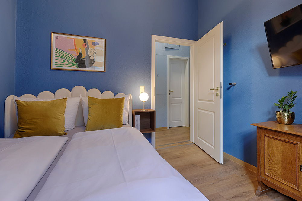 Schlafzimmer in einem Apartment in Würzburg mit blauer Wand und Türansicht