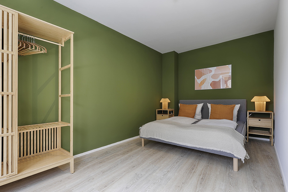 Ferienwohnung Würzburg Schlafzimmer grün modern Geräumiges Schlafzimmer einer Ferienwohnung in Würzburg mit grüner Wand und Bett