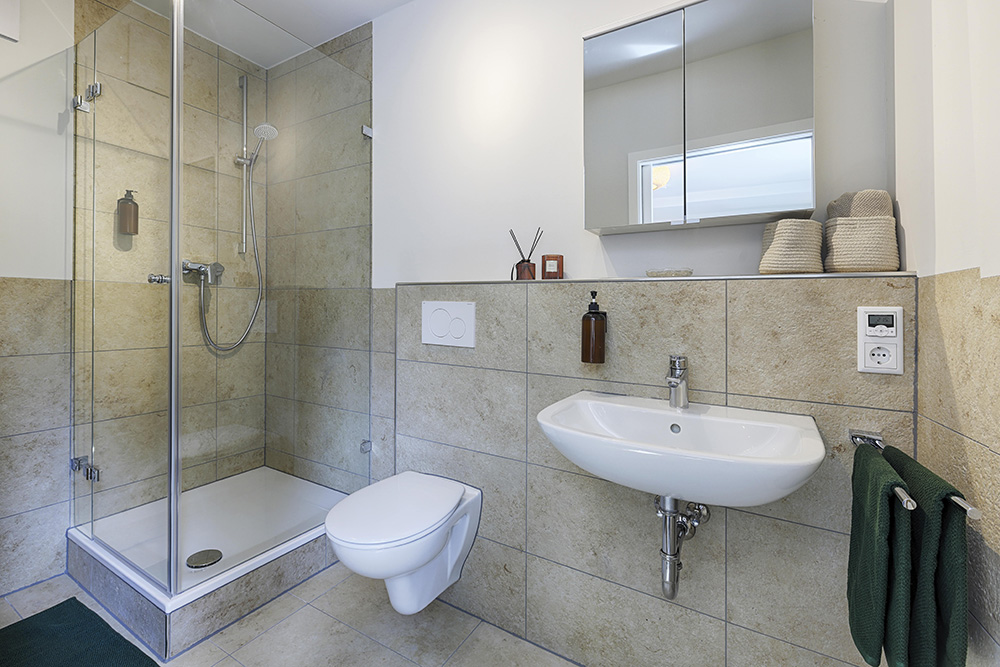Ferienwohnung Würzburg Badezimmer grau modern-min Badezimmer einer Ferienwohnung in Würzburg mit Dusche und grauen Fliesen